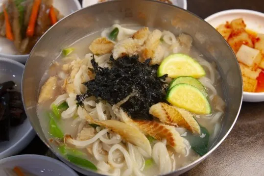 황태생칼국수 — 김가루, 애호박, 황태를 올린 칼국수, 옆에 깍두기